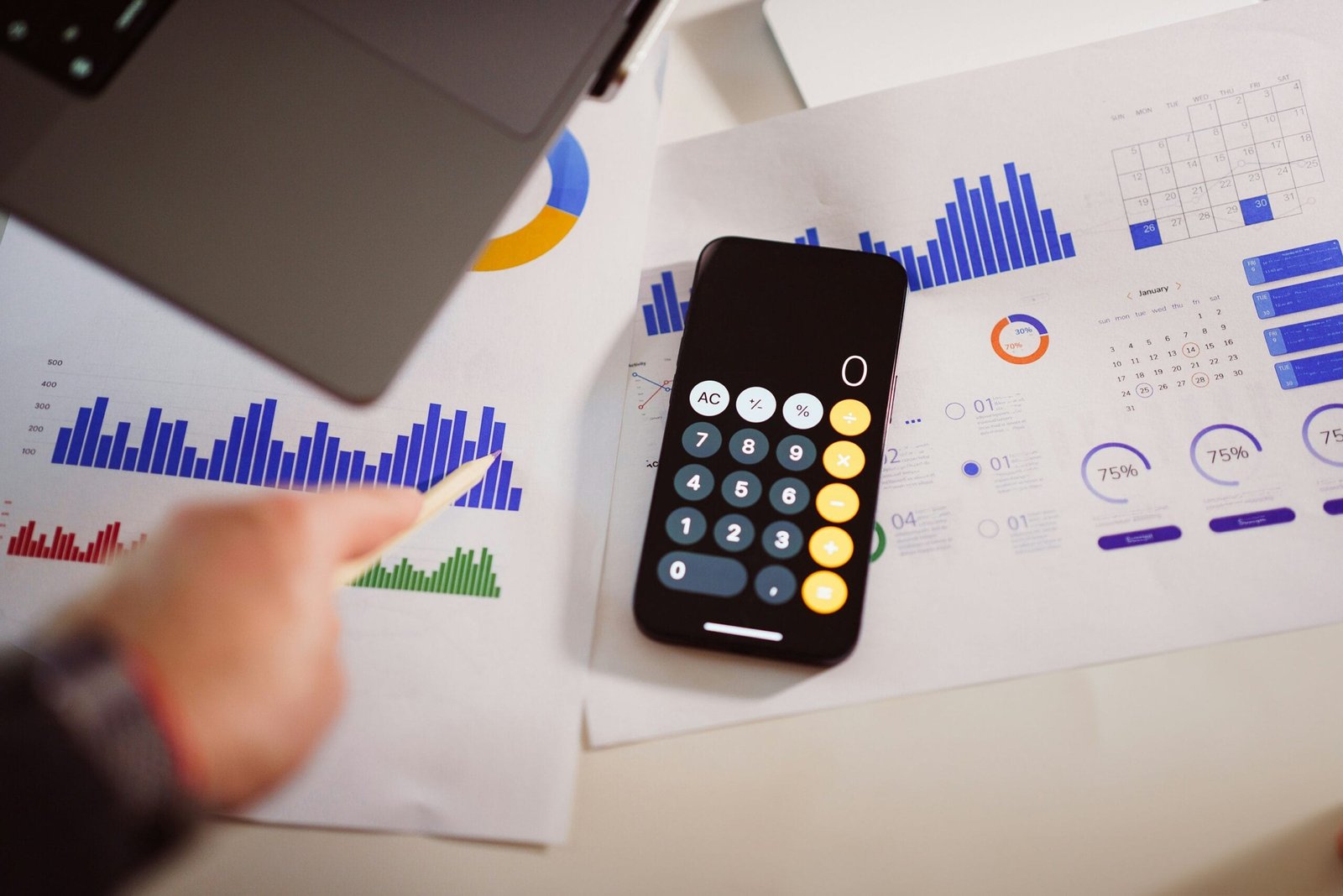 Entrepreneur using phone calculator and data-driven charts to determine how to price products on Etsy effectively